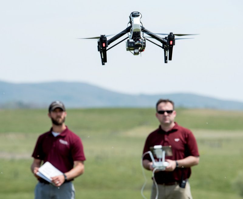 an image of a man controlling a black and gray drone