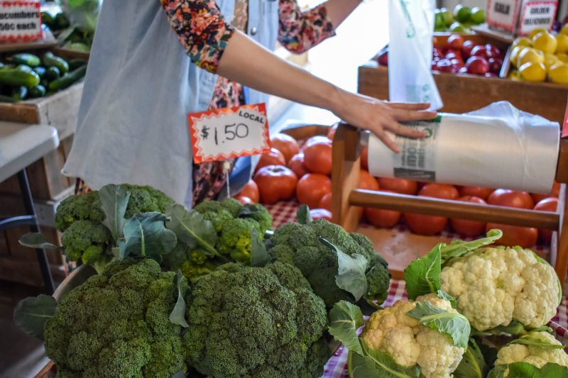 Image of produce, including broccoli, tomatoes, and cauliflower at a farmer's market